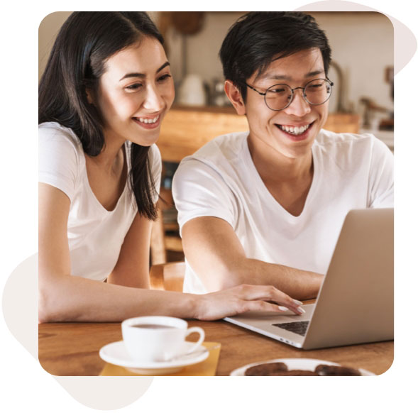 A couple sitting together on a couch, using a laptop computer.