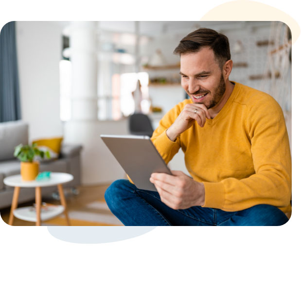 Man sitting on couch in living room, using tablet device.